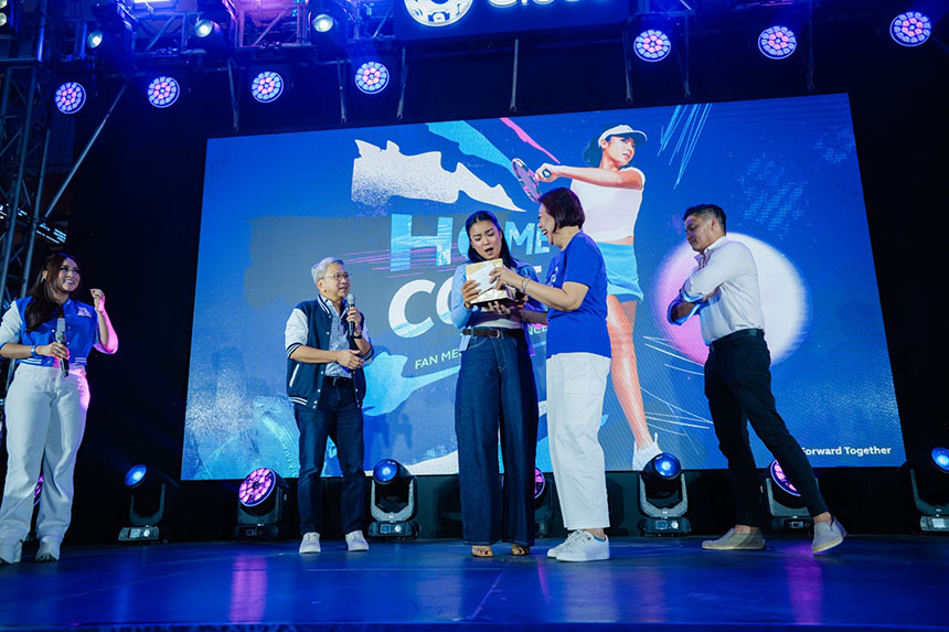 Alex Eala receives a gift on stage from Globe executives during her homecoming fan meet in Manila.