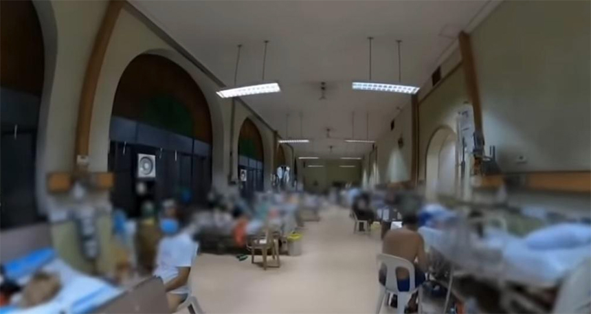 Patients resting in beds along an arched corridor at the Philippine General Hospital.
