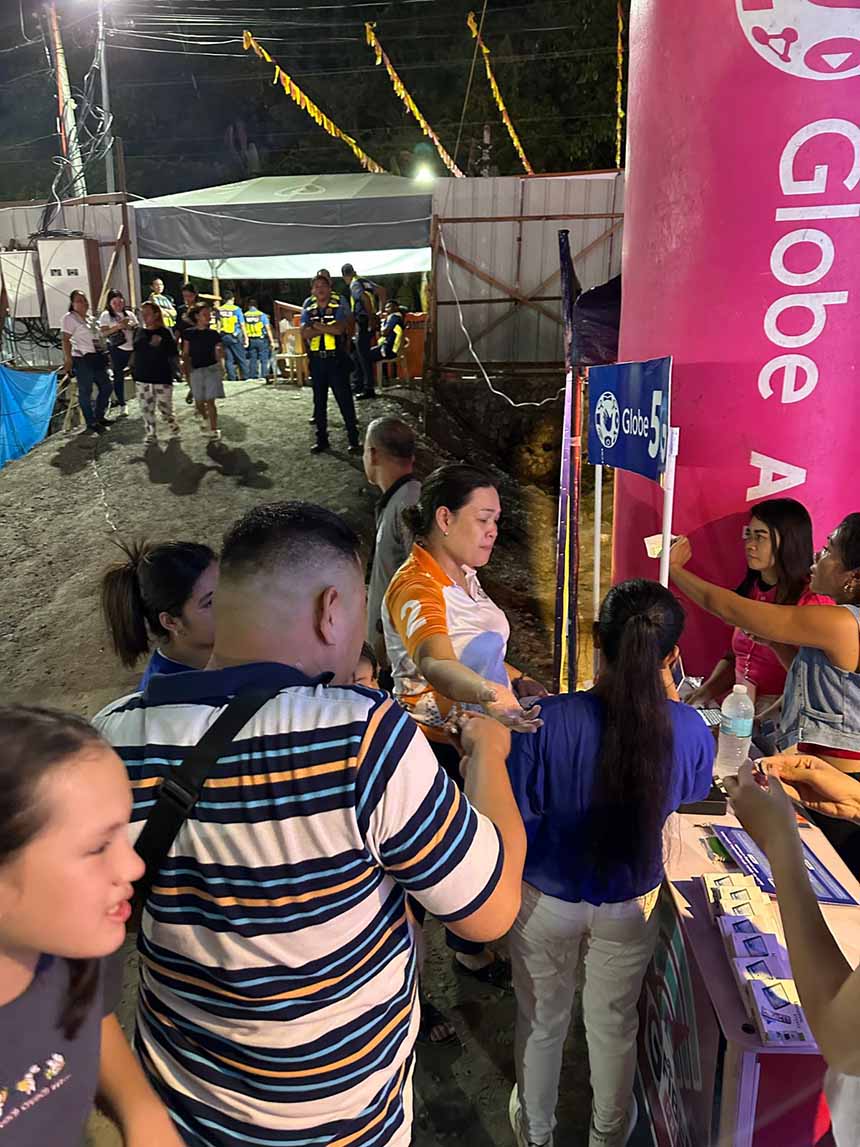 A crowd of festival-goers gathered at a Globe booth at night during Tacloban City's Sangyaw Festival.
