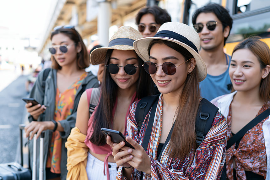 A group of travelers checks their smartphones together.