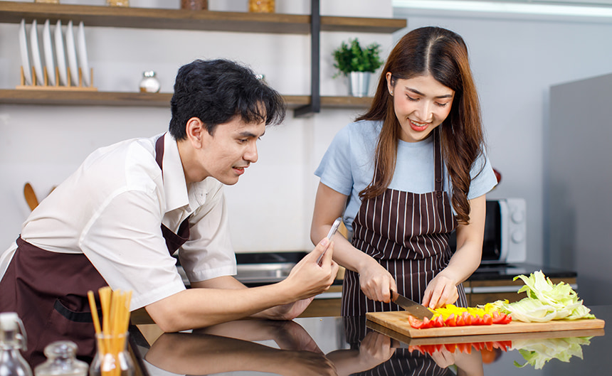 Man and woman preparing vegetables together in a kitchen.