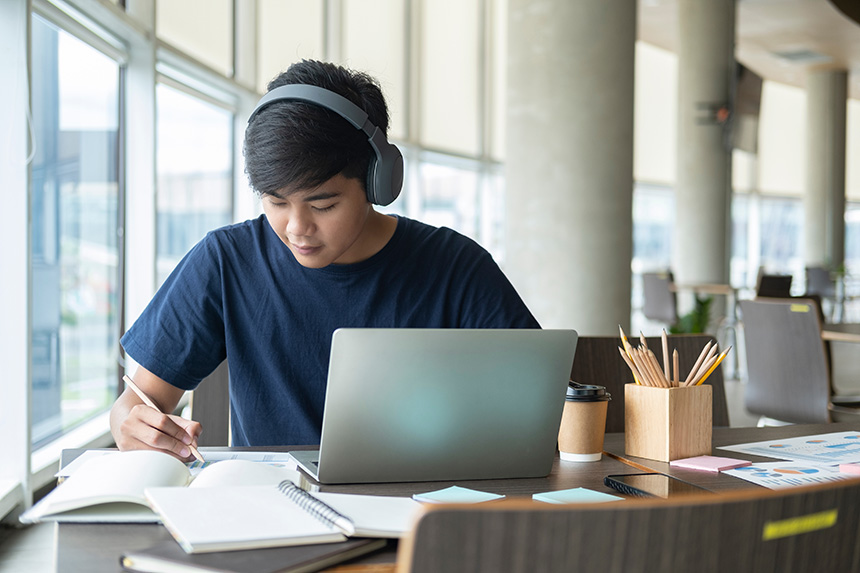Student using a laptop and notebook for online research and studying.