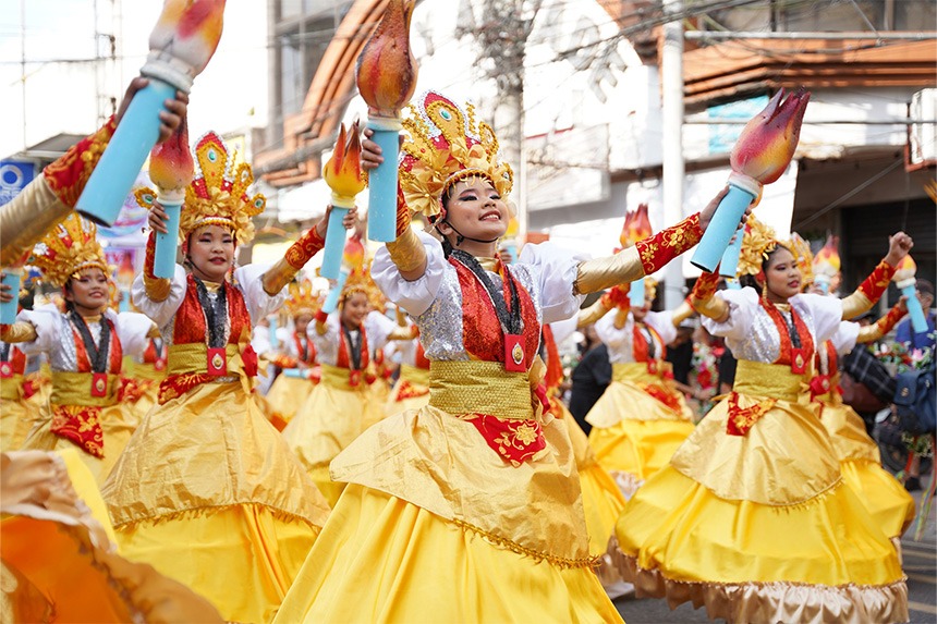 Young Asian women in bright yellow and gold costumes dancing at the PeÃ±afrancia Voyadores Festival.