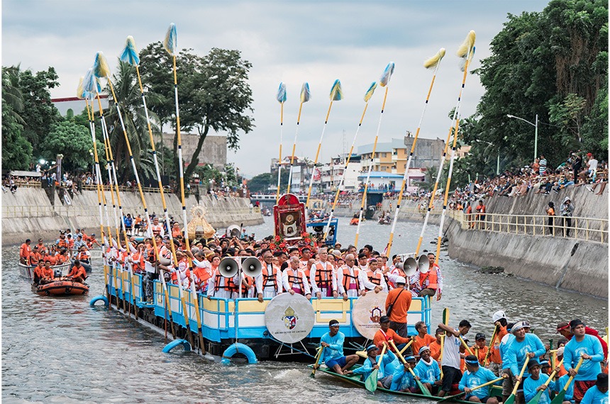 Our Lady of PeÃ±afrancia and the Divino Rostro surrounded by priests and officials on a barge.