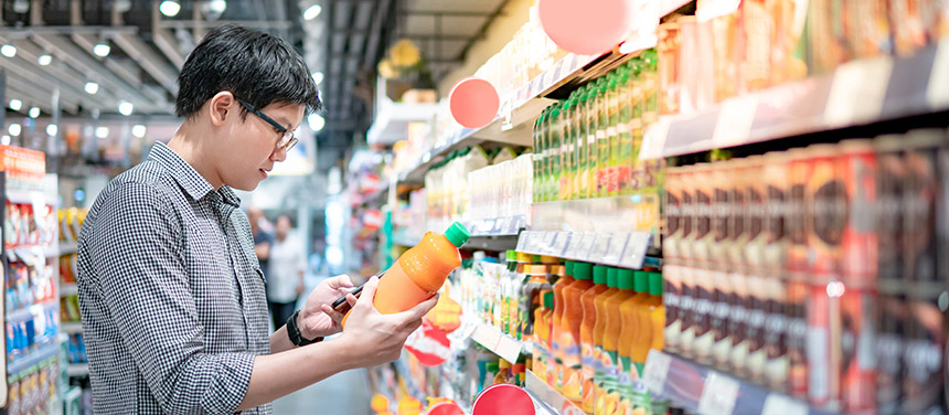Man checking a bottled product while shopping in a store.